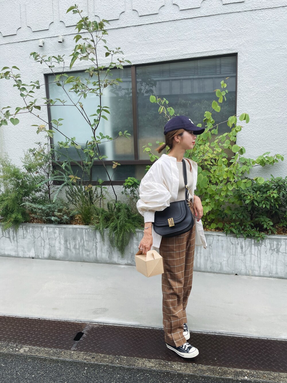 ベージュ系のタンクトップ、ブラウン系のパンツ、ブラック系のショルダーバッグを着用したレディースの秋コーディネートの2枚目の写真