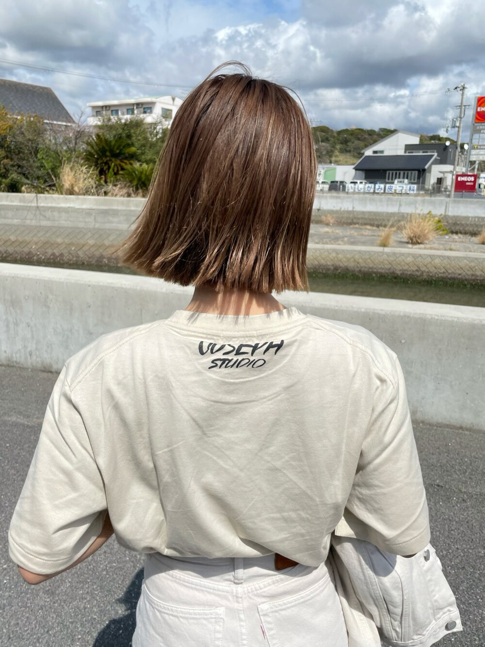 ホワイト系のデニムパンツ、ベージュ系のトレンチコート、ベージュ系のTシャツ/カットソーを着用したレディースの春コーディネートの3枚目の写真