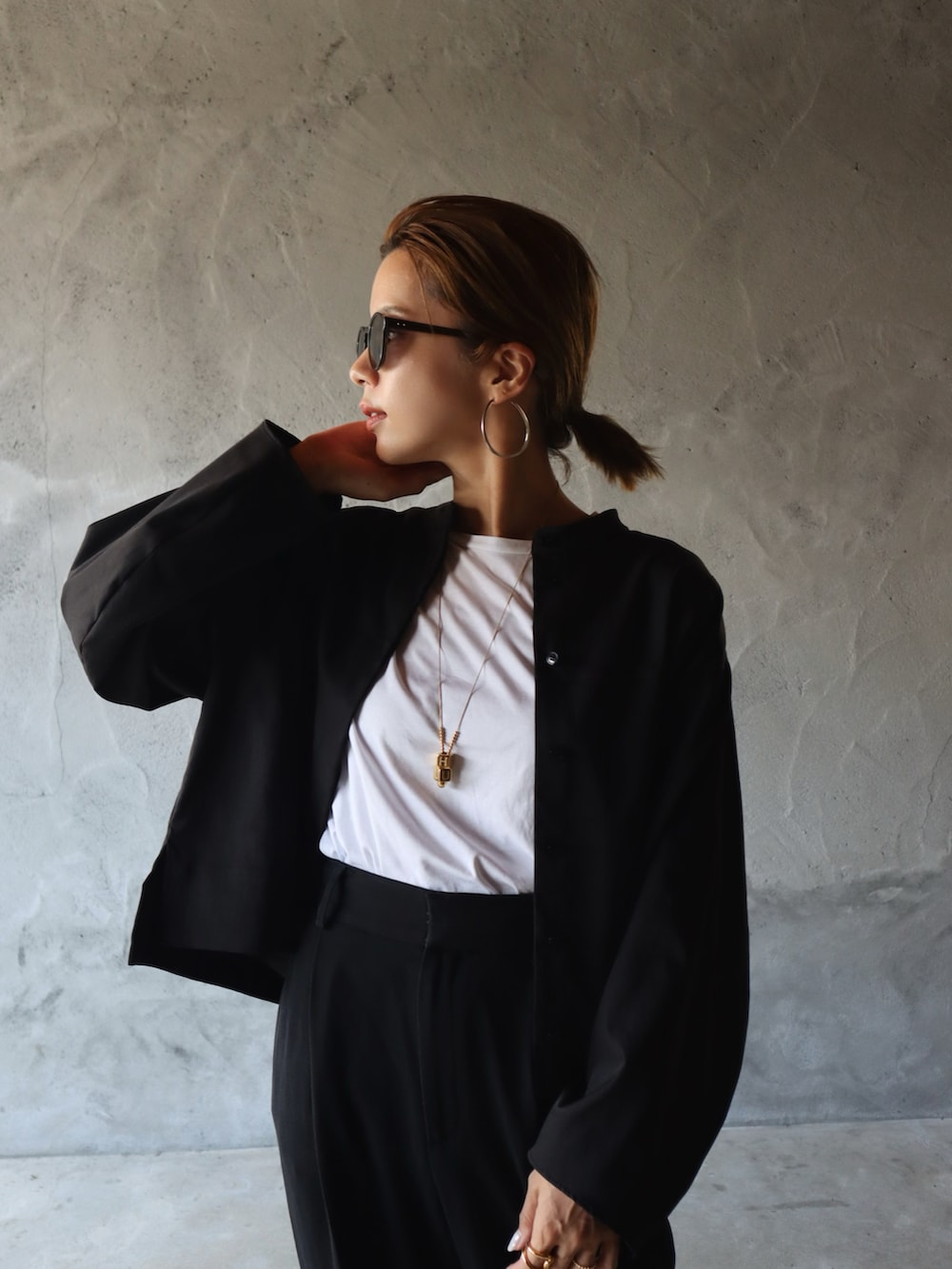 ブラック系のシャツ/ブラウス、ブラック系のスラックス、ホワイト系のスニーカーを着用したレディースの夏コーディネートの3枚目の写真