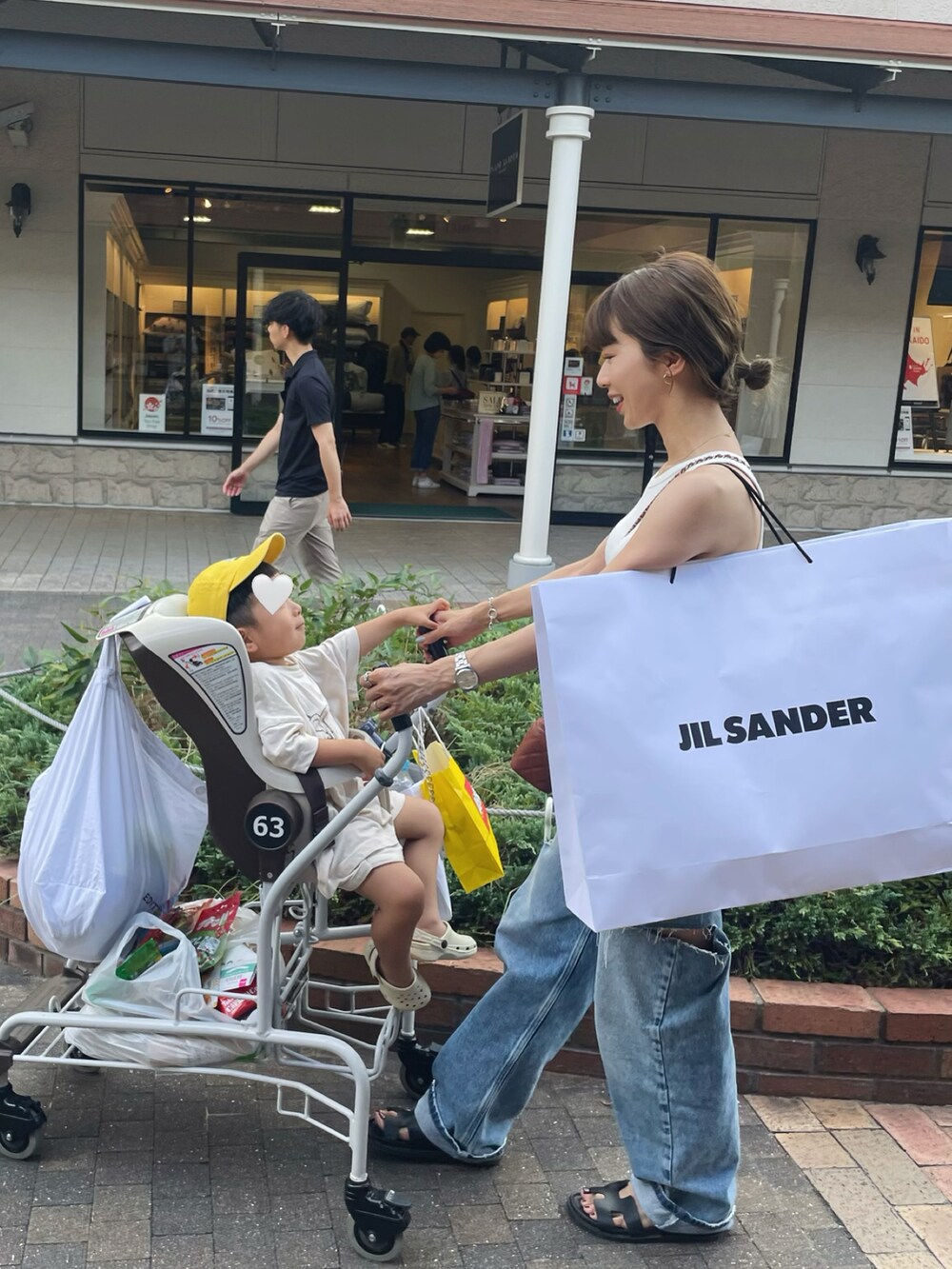 ブルー系のデニムパンツ、ホワイト系のアンダーウェア、ブラック系のベルトを着用したレディースの夏コーディネートの2枚目の写真