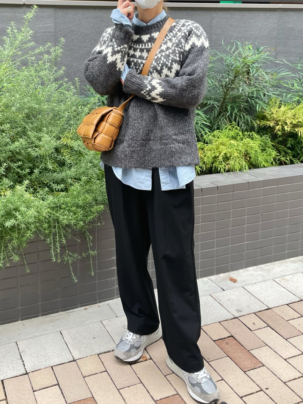 グレー系のニット/セーター、ブルー系のシャツ/ブラウス、ブラック系のスラックスを着用したレディースの秋コーディネートの2枚目の写真