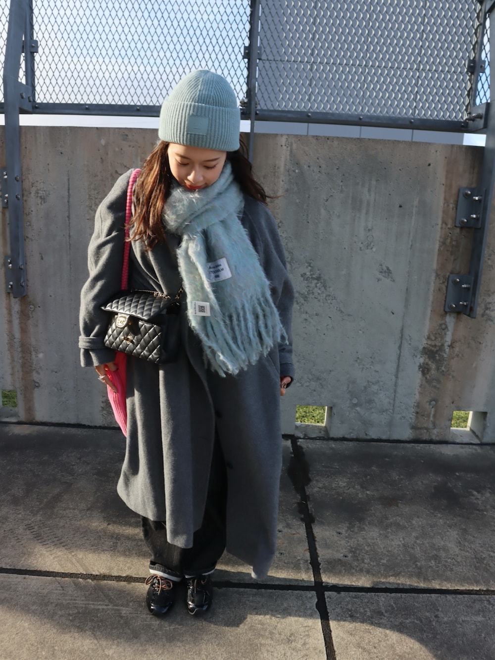 グレー系のチェスターコート、ブルー系のマフラー、ブルー系のニットキャップ/ビーニーを着用したレディースの秋コーディネートの2枚目の写真