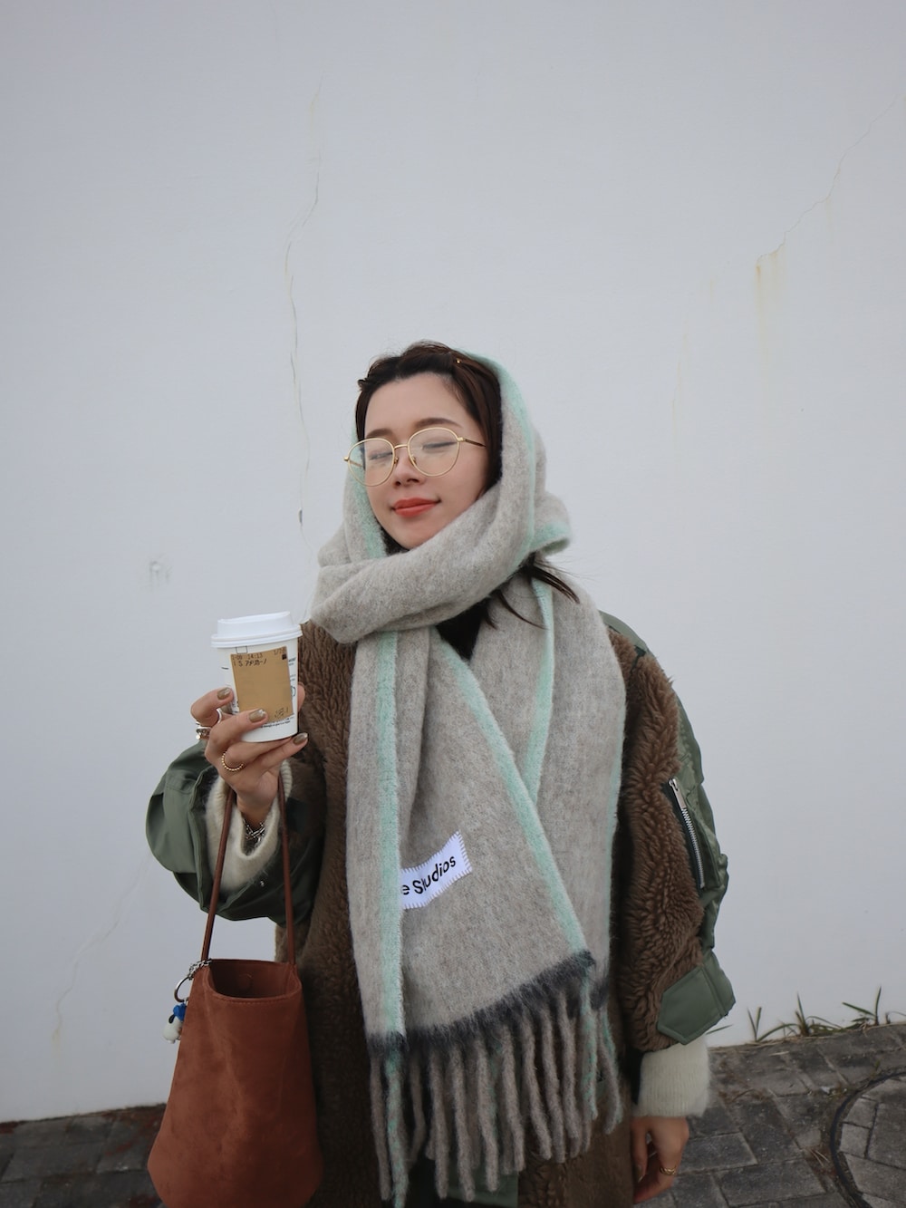 グレー系のスカート、ブラック系のスニーカー、ブラウン系のハンドバッグを着用したレディースの冬コーディネートの2枚目の写真