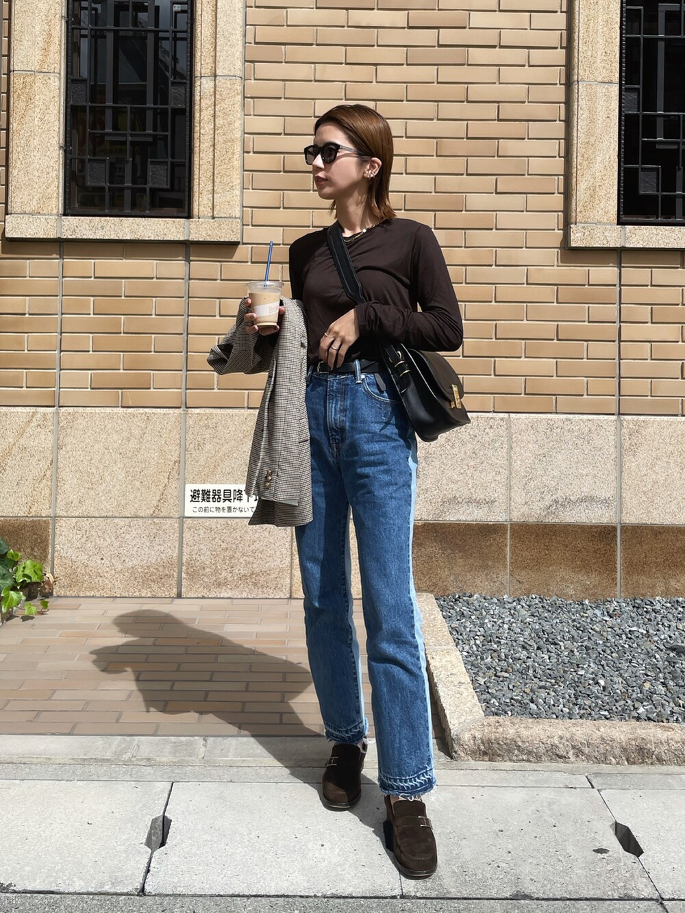 ブラウン系のTシャツ/カットソー、ブルー系のデニムパンツ、ブラック系のショルダーバッグを着用したレディースの秋コーディネートの2枚目の写真