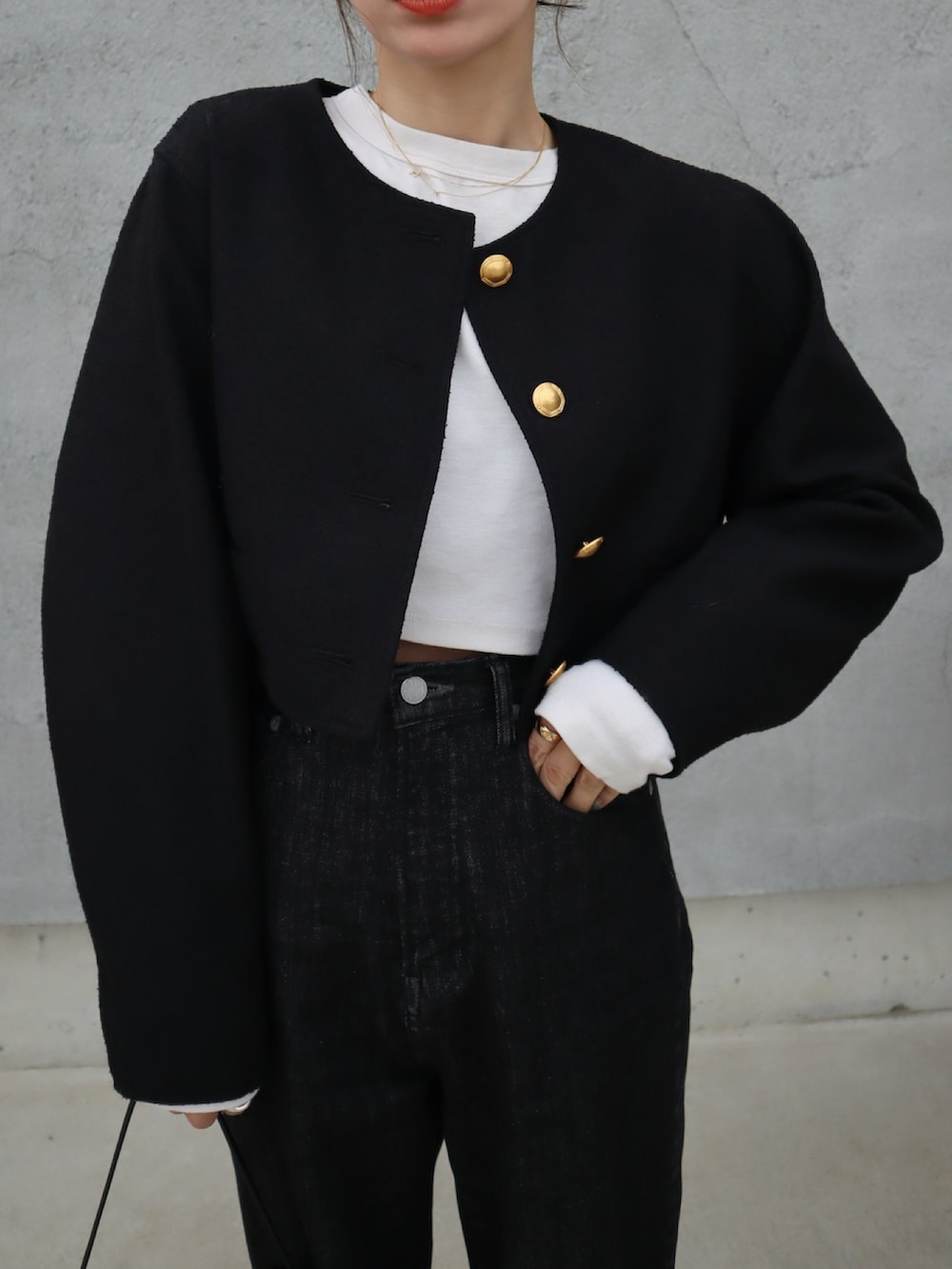 ブラック系のデニムパンツ、ブラック系のノーカラージャケット、ホワイト系のTシャツ/カットソーを着用したレディースの春コーディネートの2枚目の写真