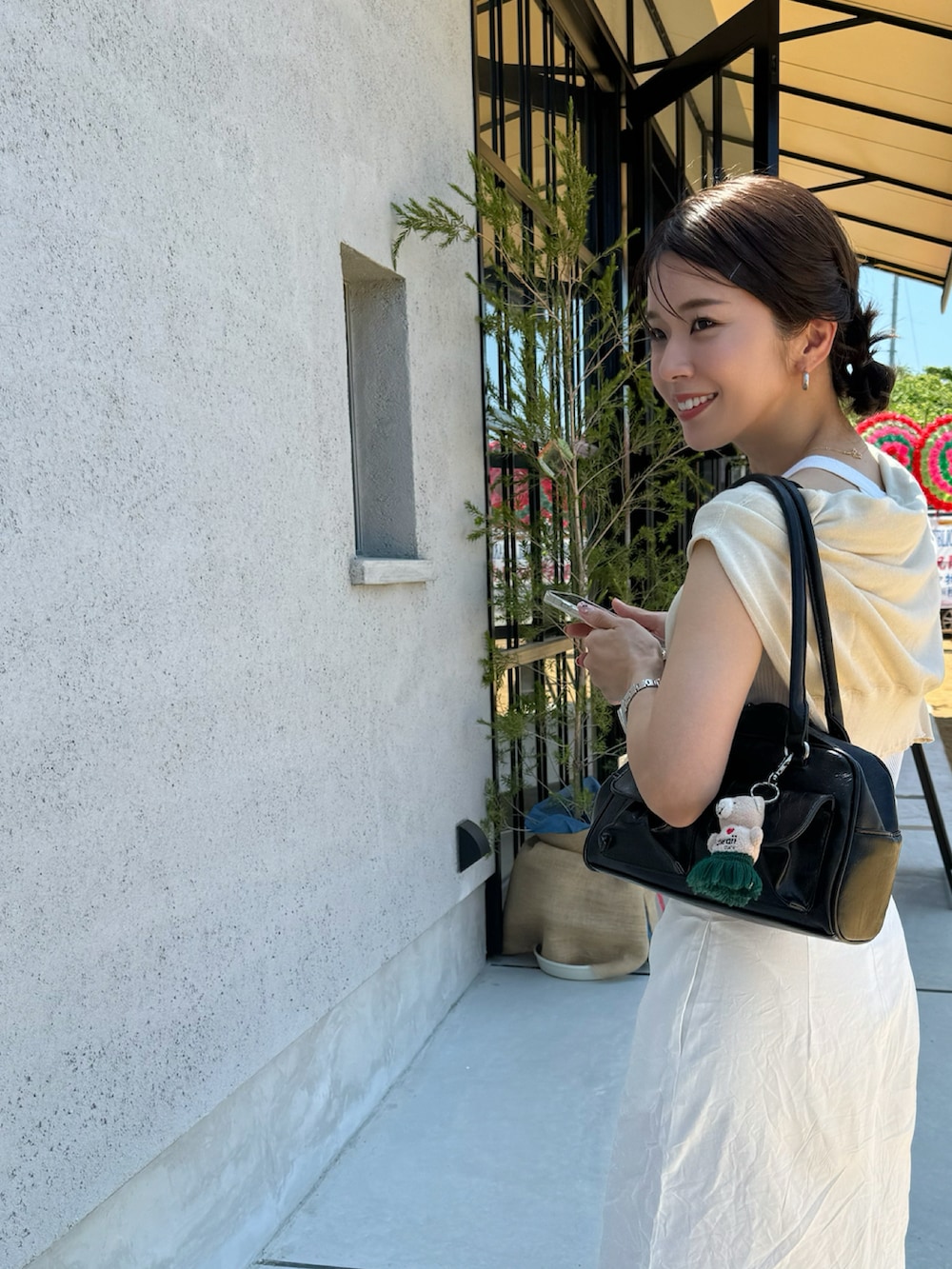 ブラック系のボストンバッグ、ブルー系のスニーカー、ホワイト系のスカートを着用したレディースの夏コーディネートの2枚目の写真