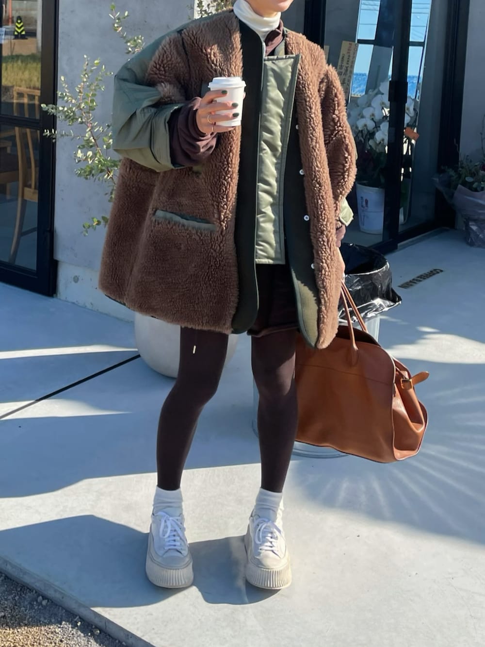 グリーン系のその他アウター、ブラウン系のスウェット、ホワイト系のスニーカーを着用したレディースの冬コーディネートの2枚目の写真