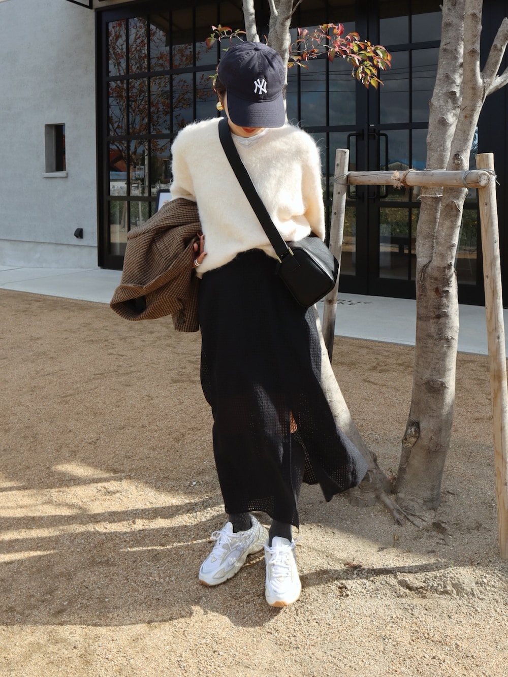 イエロー系のテーラードジャケット、ホワイト系のニット/セーター、ブラック系のスカートを着用したレディースの秋コーディネートの2枚目の写真