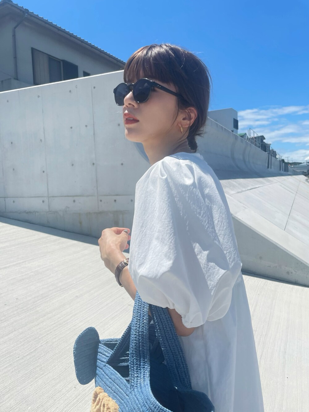 ブルー系のトートバッグ、ホワイト系のワンピース、グリーン系のサングラスを着用したレディースの夏コーディネートの2枚目の写真