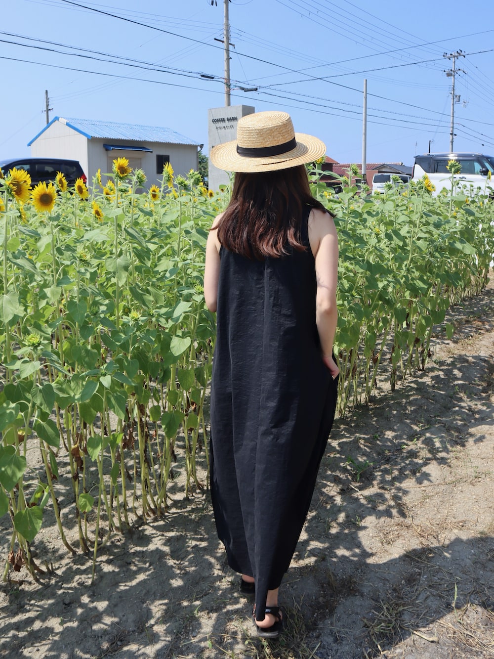 ブラック系のワンピース、ブラウン系のサンダルを着用したレディースの夏コーディネートの2枚目の写真