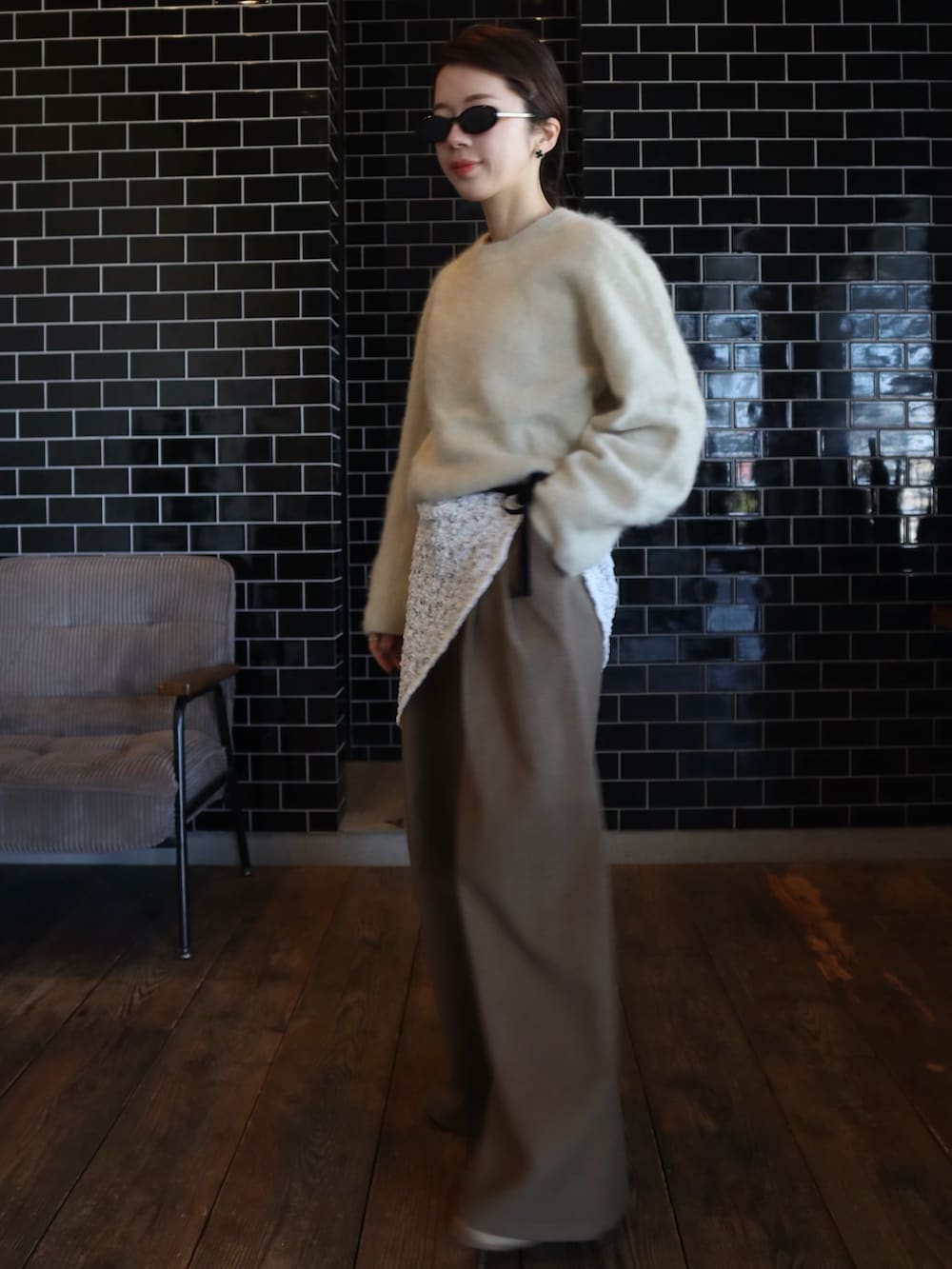 ベージュ系のニット/セーター、ブラウン系のスラックス、ホワイト系のストール/ショールを着用したレディースの冬コーディネートの2枚目の写真