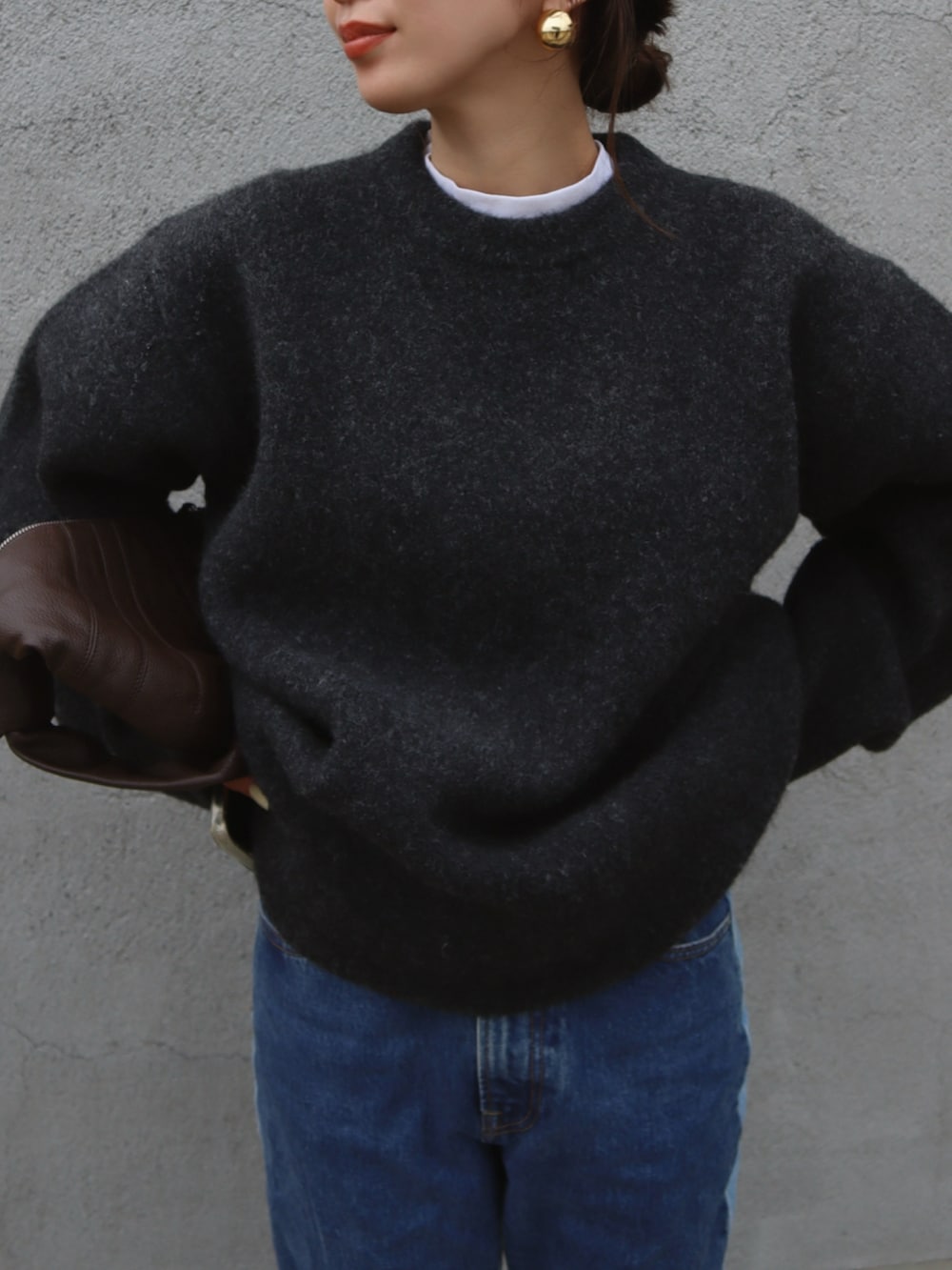 グレー系のニット/セーター、ブルー系のデニムパンツ、ブラウン系のショルダーバッグを着用したレディースの秋コーディネートの2枚目の写真