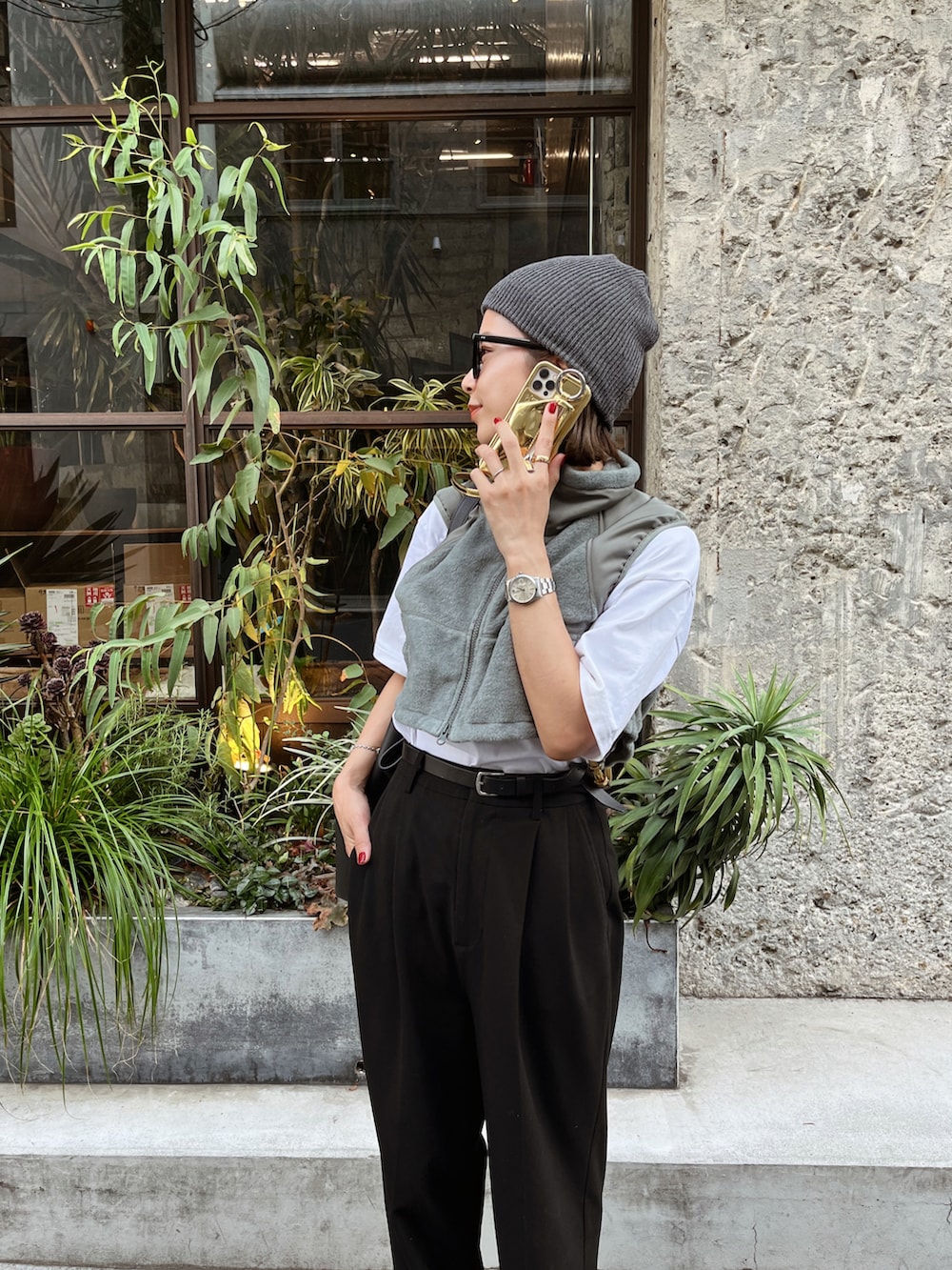 グリーン系のベスト、ブラック系のスラックス、ブラック系のスニーカーを着用したレディースの秋コーディネートの2枚目の写真