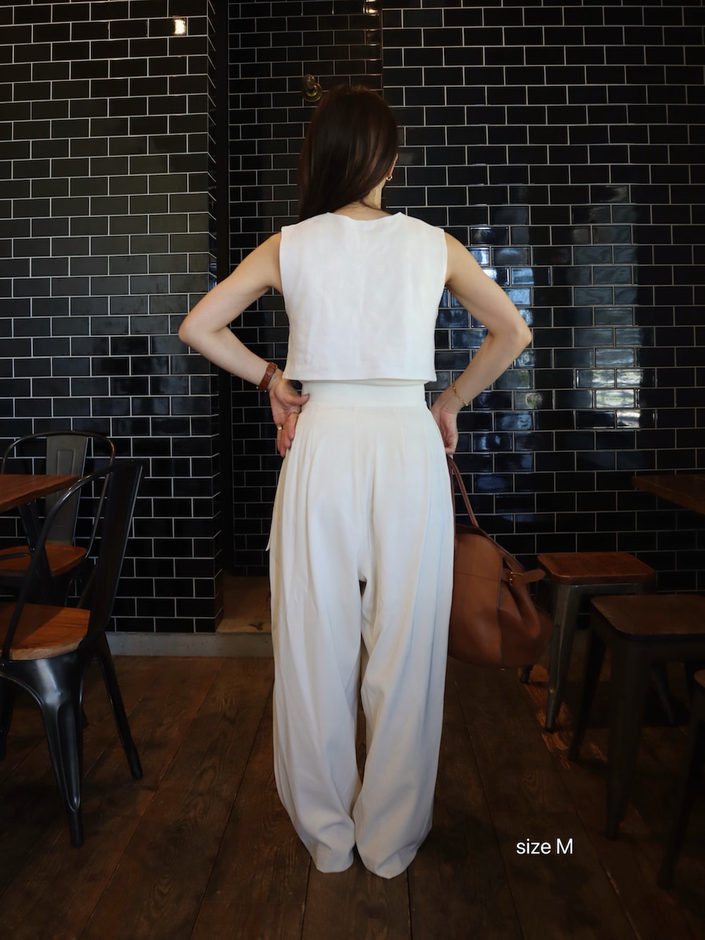 ホワイト系のTシャツ/カットソー、ホワイト系のスラックス、ブラウン系のハンドバッグを着用したレディースの夏コーディネートの3枚目の写真