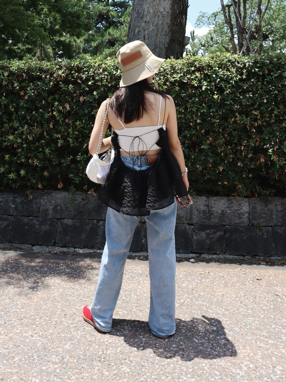 ブルー系のデニムパンツ、ブラック系のその他トップス、レッド系のスニーカーを着用したレディースの夏コーディネートの2枚目の写真