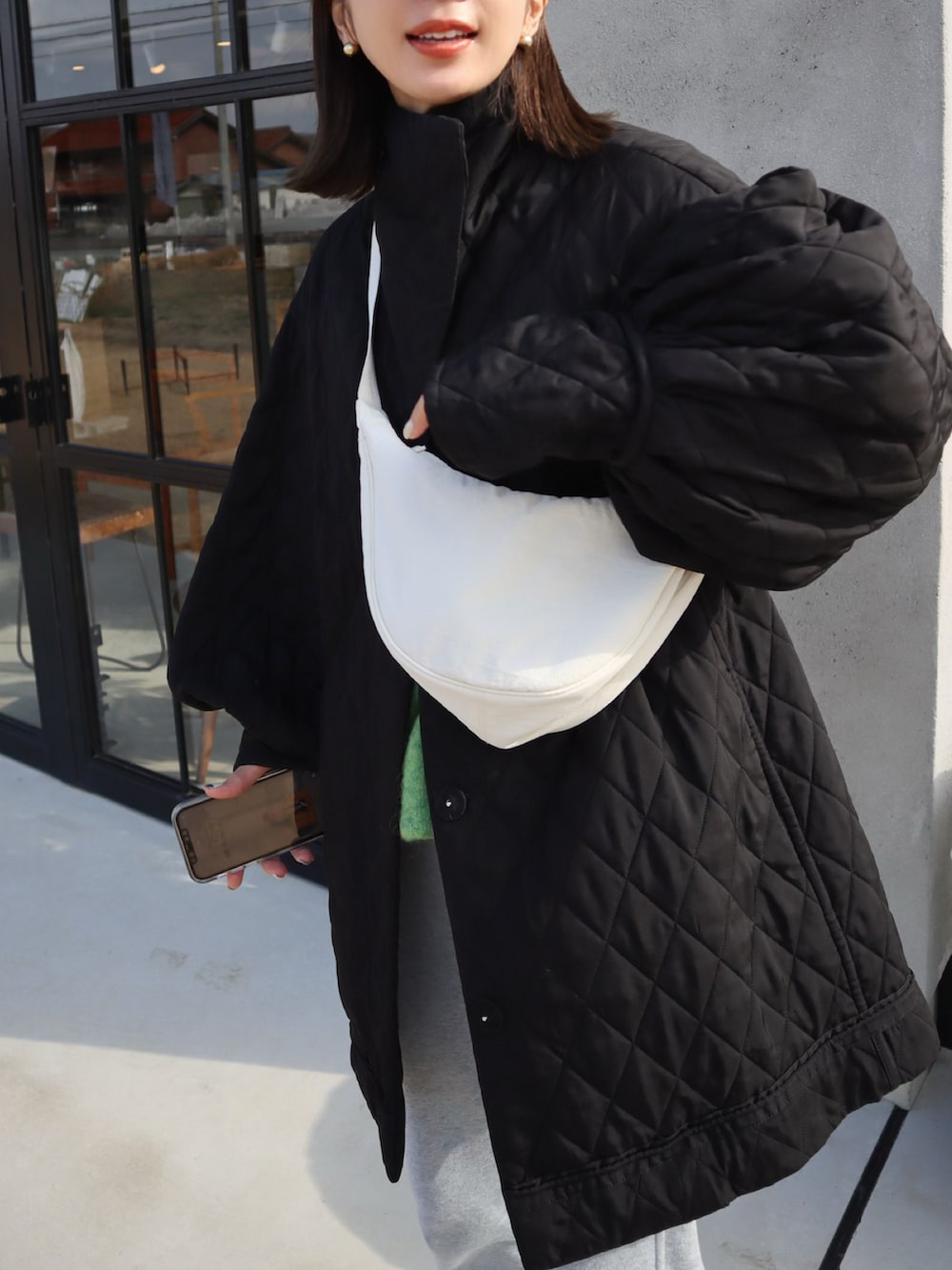 ホワイト系のショルダーバッグ、グレー系のスウェットパンツ、グレー系のスニーカーを着用したレディースの冬コーディネートの2枚目の写真