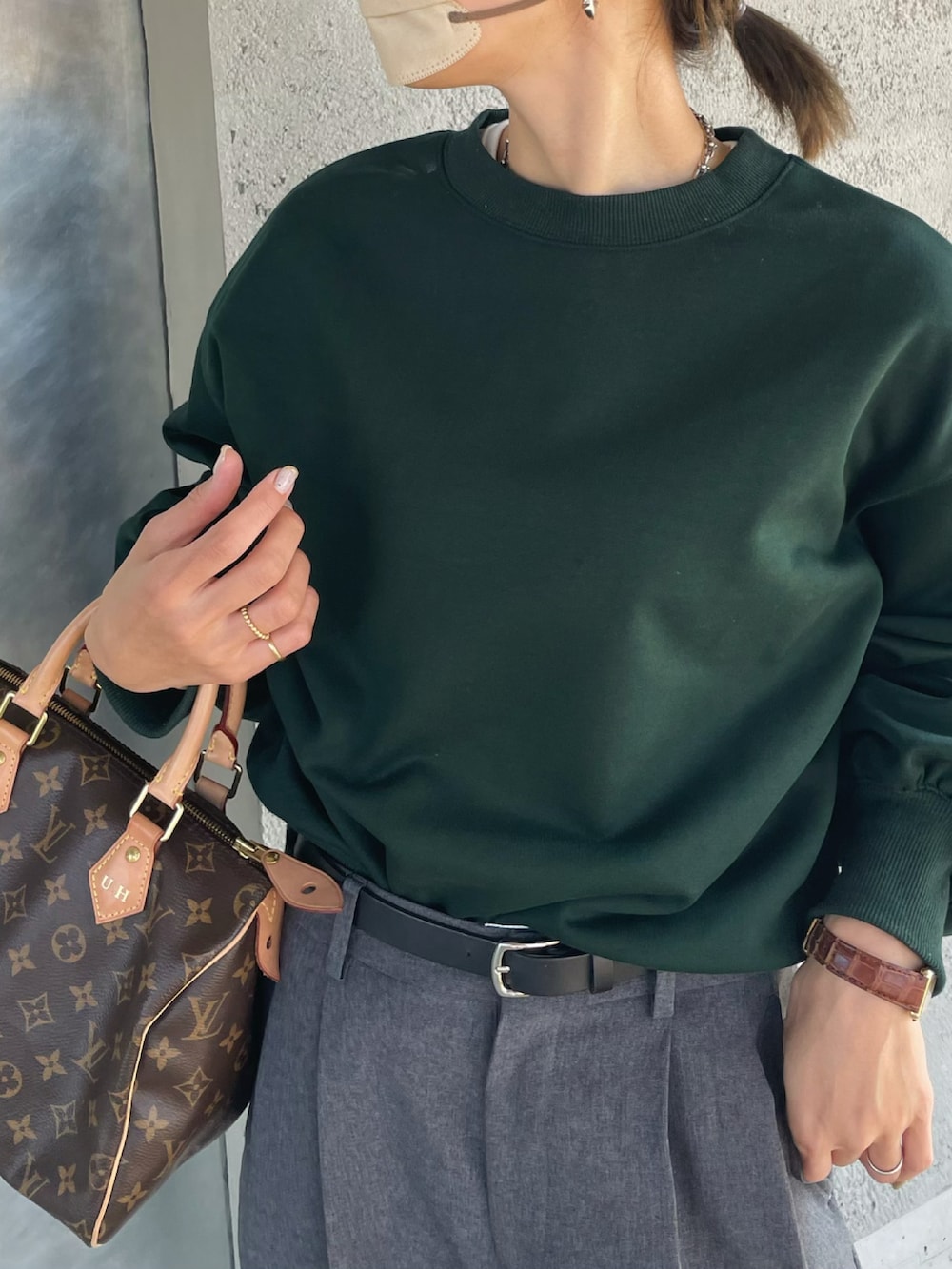 グリーン系のスウェット、グレー系のスラックス、ブラウン系のハンドバッグを着用したレディースの冬コーディネートの3枚目の写真