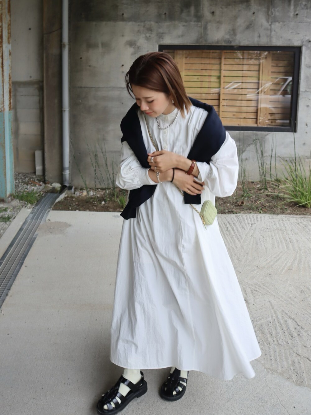 ブルー系のスウェット、ホワイト系のシャツワンピース、ブラック系のサンダルを着用したレディースの春コーディネートの2枚目の写真