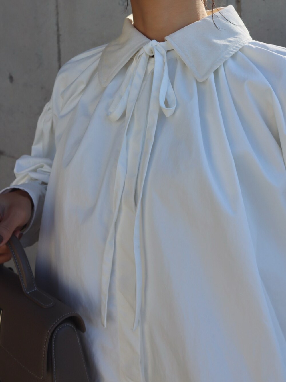 ホワイト系のシャツワンピース、ブラック系のパンプスを着用したレディースの冬コーディネートの2枚目の写真