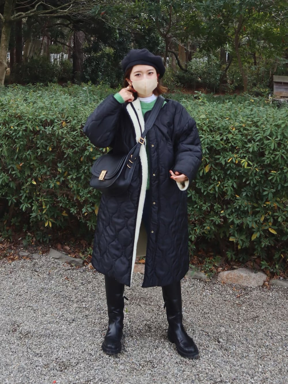 グリーン系のニット/セーター、ブラック系のショルダーバッグ、ブルー系のデニムパンツを着用したレディースの冬コーディネートの2枚目の写真