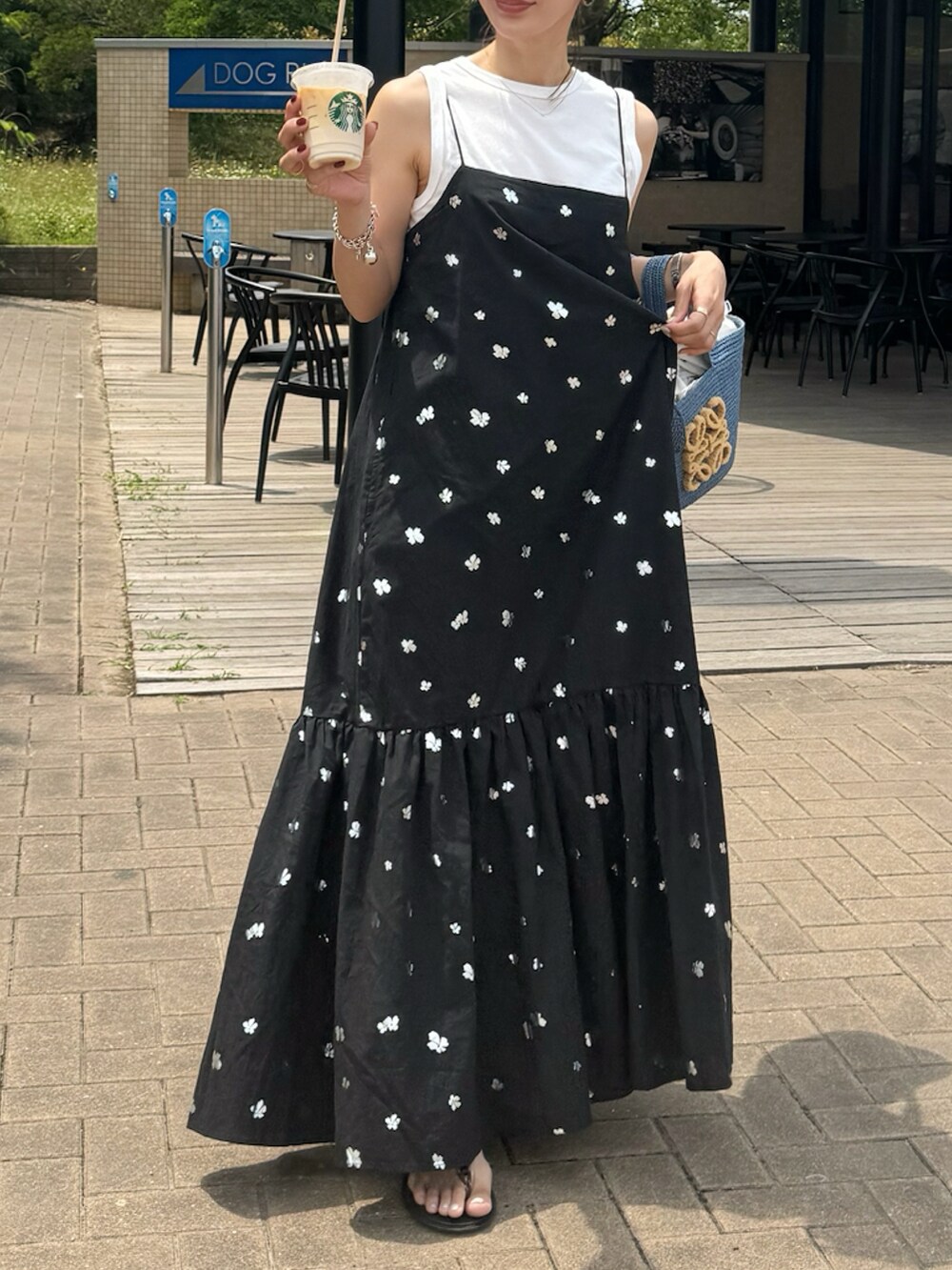 ブルー系のトートバッグ、ブラック系のワンピースを着用したレディースの夏コーディネートの2枚目の写真