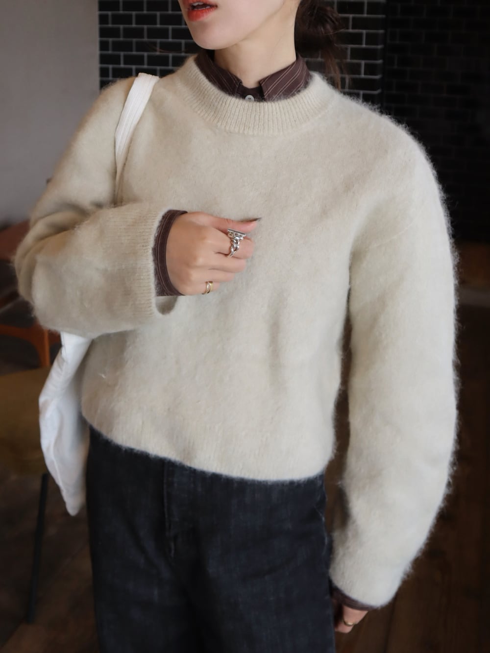 ベージュ系のニット/セーター、ブラック系のデニムパンツ、ブラック系のスニーカーを着用したレディースの冬コーディネートの2枚目の写真