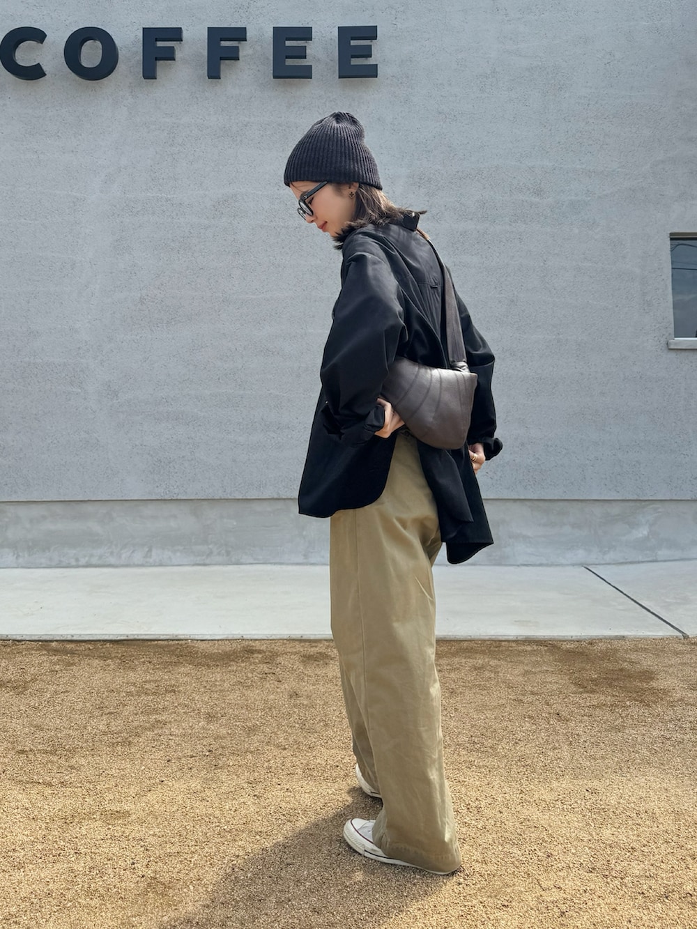 ブラック系のシャツ/ブラウス、ベージュ系のチノパンツ、ホワイト系のスニーカーを着用したレディースの秋コーディネートの3枚目の写真