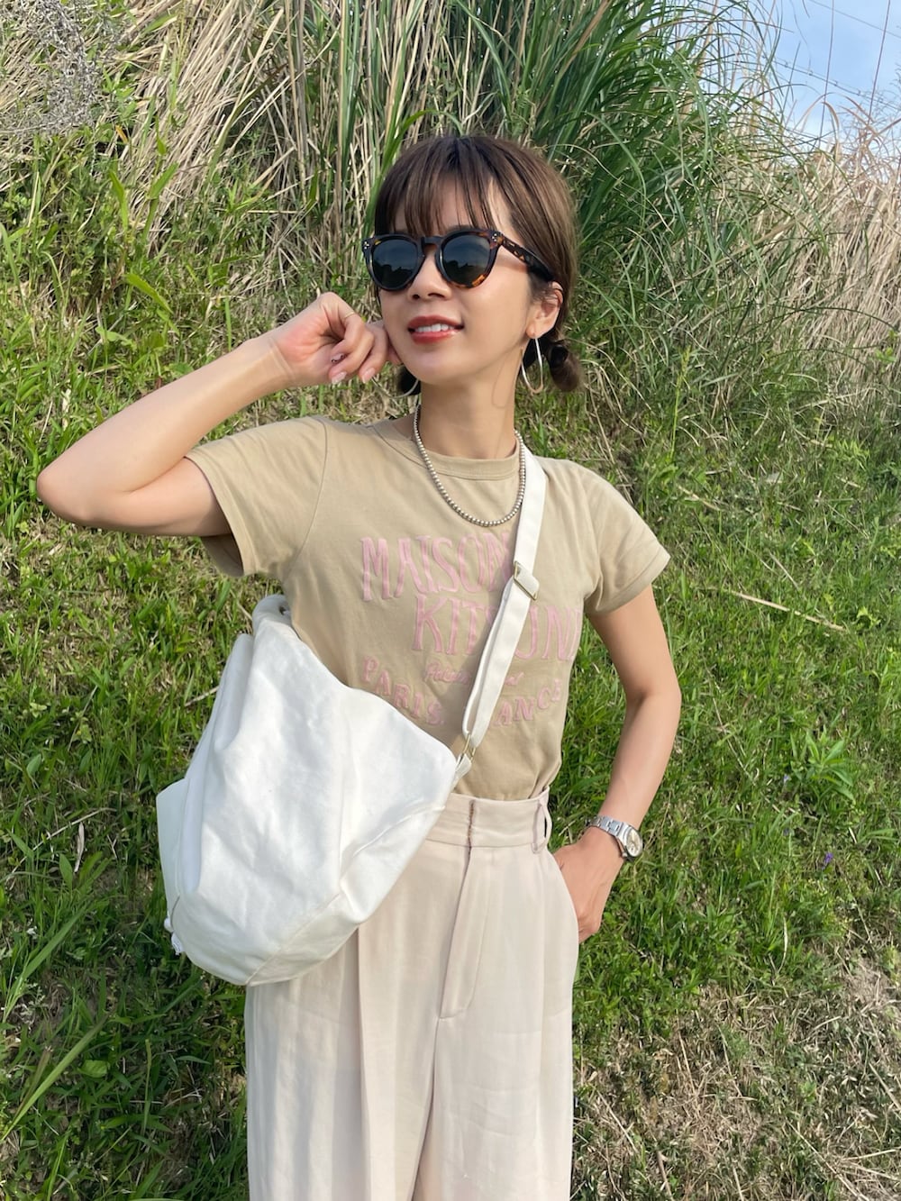 ベージュ系のTシャツ/カットソー、ホワイト系のスラックス、ホワイト系のバックパック/リュックを着用したレディースの春コーディネートの2枚目の写真