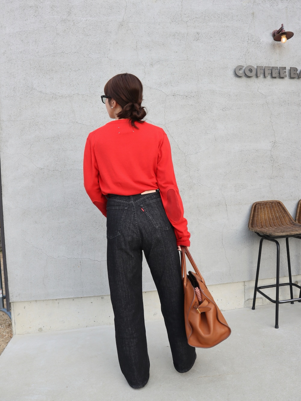 レッド系のニット/セーター、ホワイト系のTシャツ/カットソー、ブラック系のデニムパンツを着用したレディースの春コーディネートの2枚目の写真