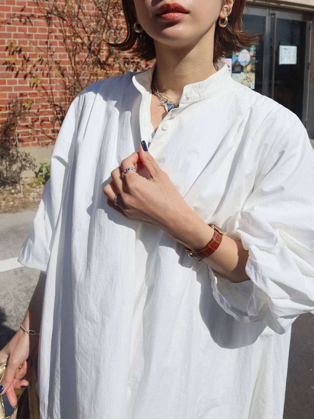 ホワイト系のシャツワンピース、ゴールド系のエコバッグ/サブバッグ、ブラウン系のサンダルを着用したレディースの冬コーディネートの3枚目の写真