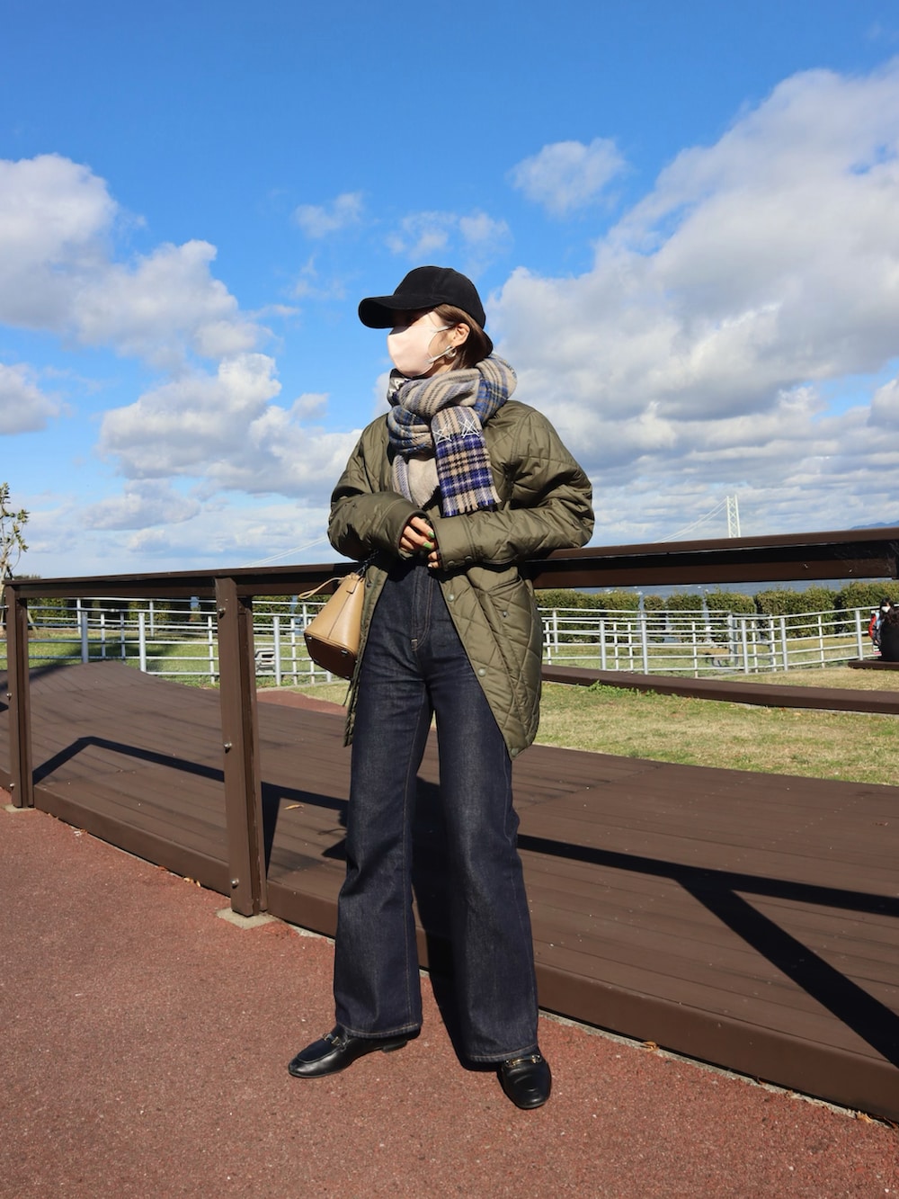 グリーン系のジャケット/アウター、ホワイト系のニット/セーター、ブルー系のデニムパンツを着用したレディースの秋コーディネートの2枚目の写真