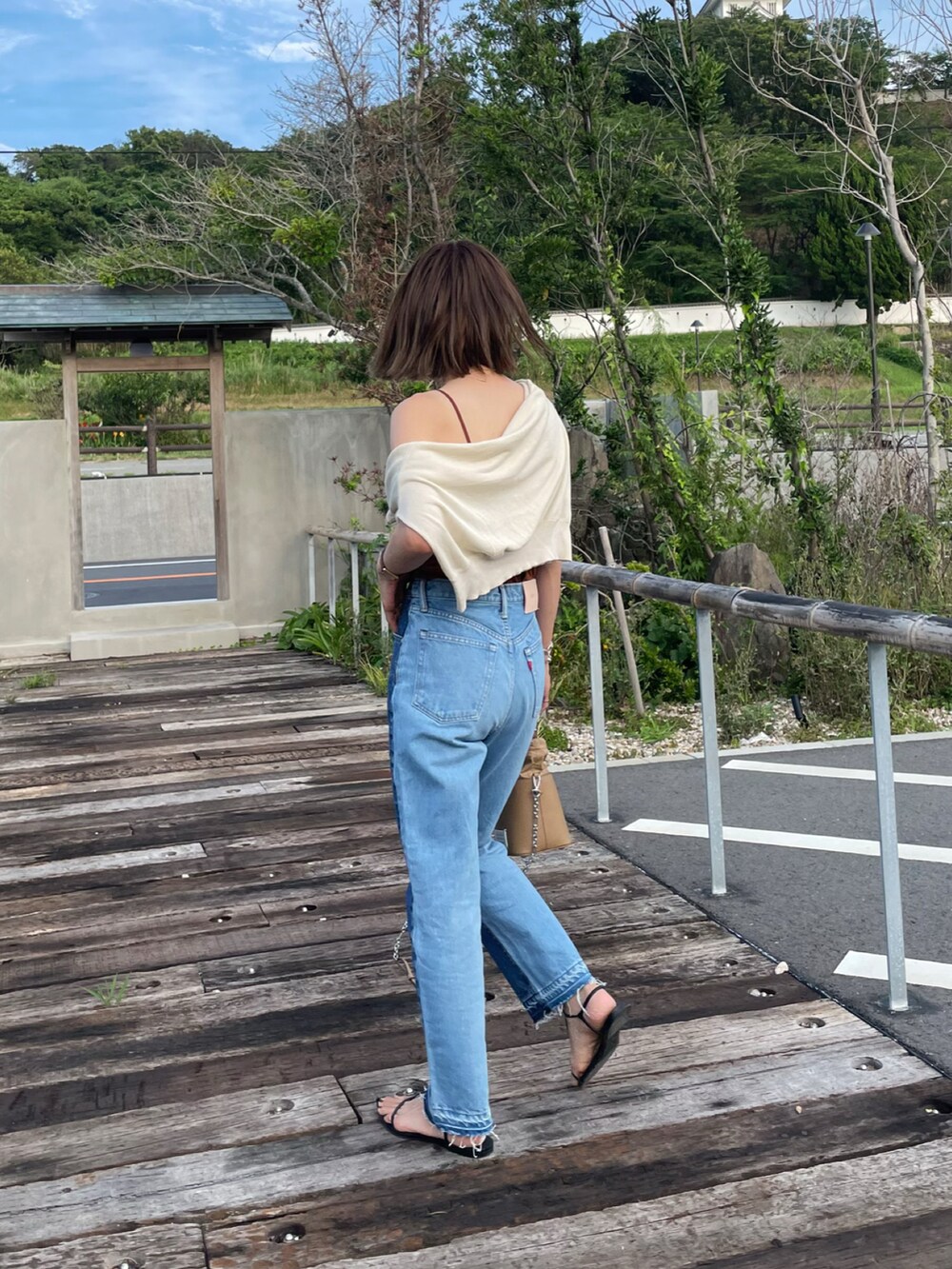 ホワイト系のニット/セーター、ブルー系のデニムパンツ、ブラック系のサンダルを着用したレディースの夏コーディネートの2枚目の写真