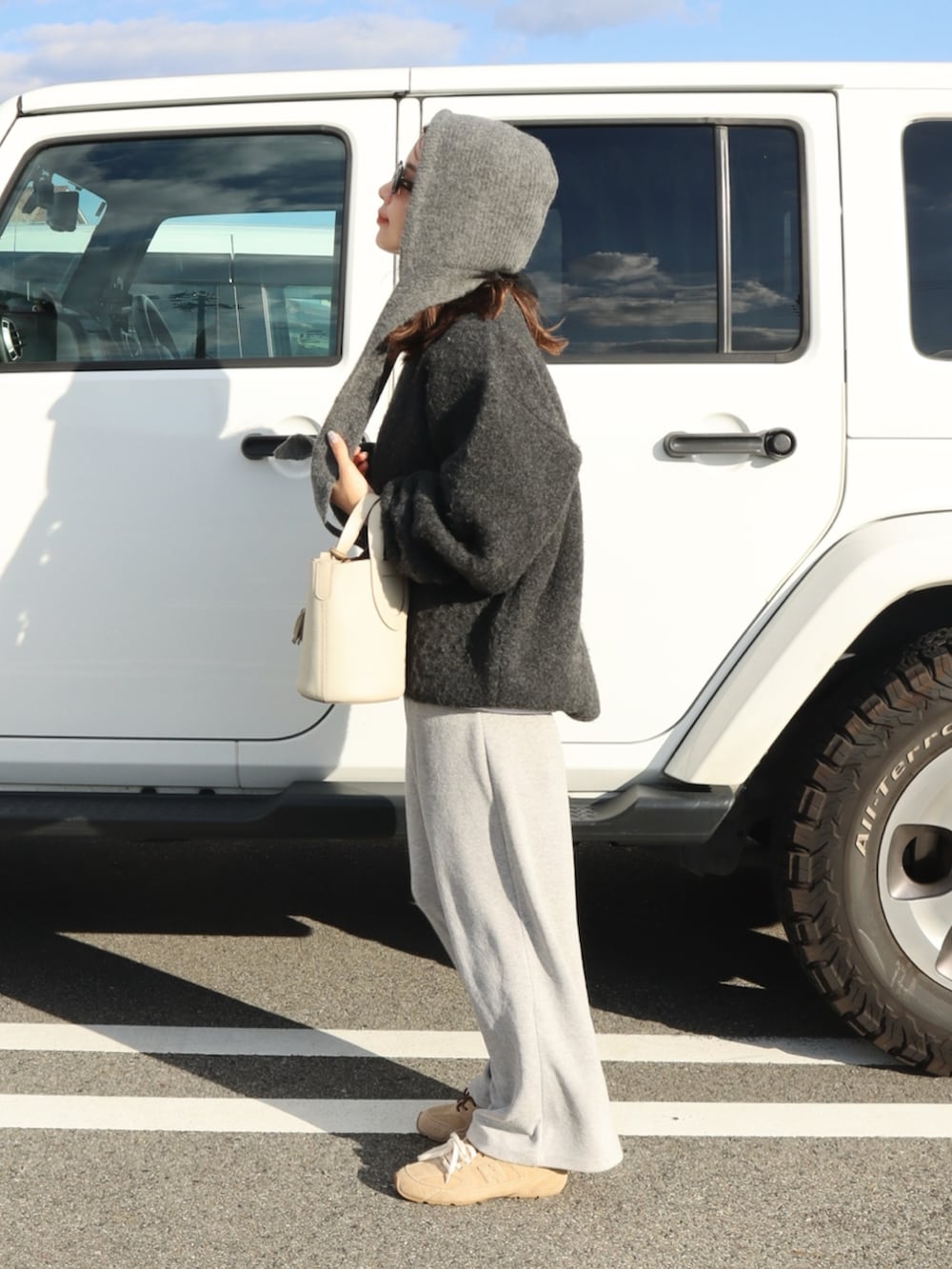 グレー系のニット/セーター、グレー系のスウェットパンツ、ベージュ系のスニーカーを着用したレディースの秋コーディネートの2枚目の写真