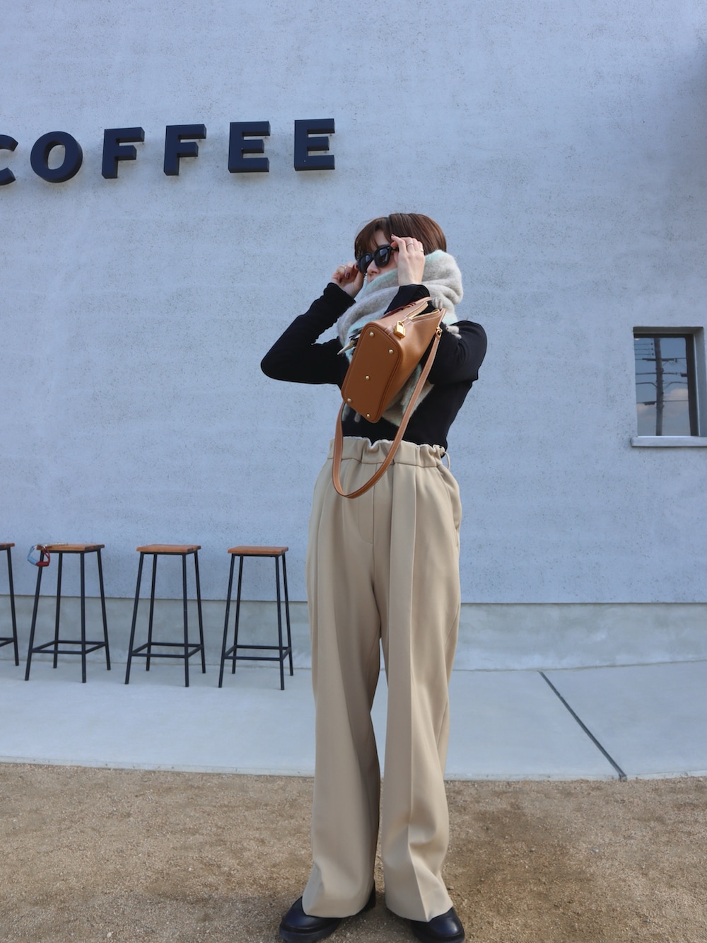 ブラック系のTシャツ/カットソー、ブラック系のその他アウター、ベージュ系のスラックスを着用したレディースの冬コーディネートの2枚目の写真