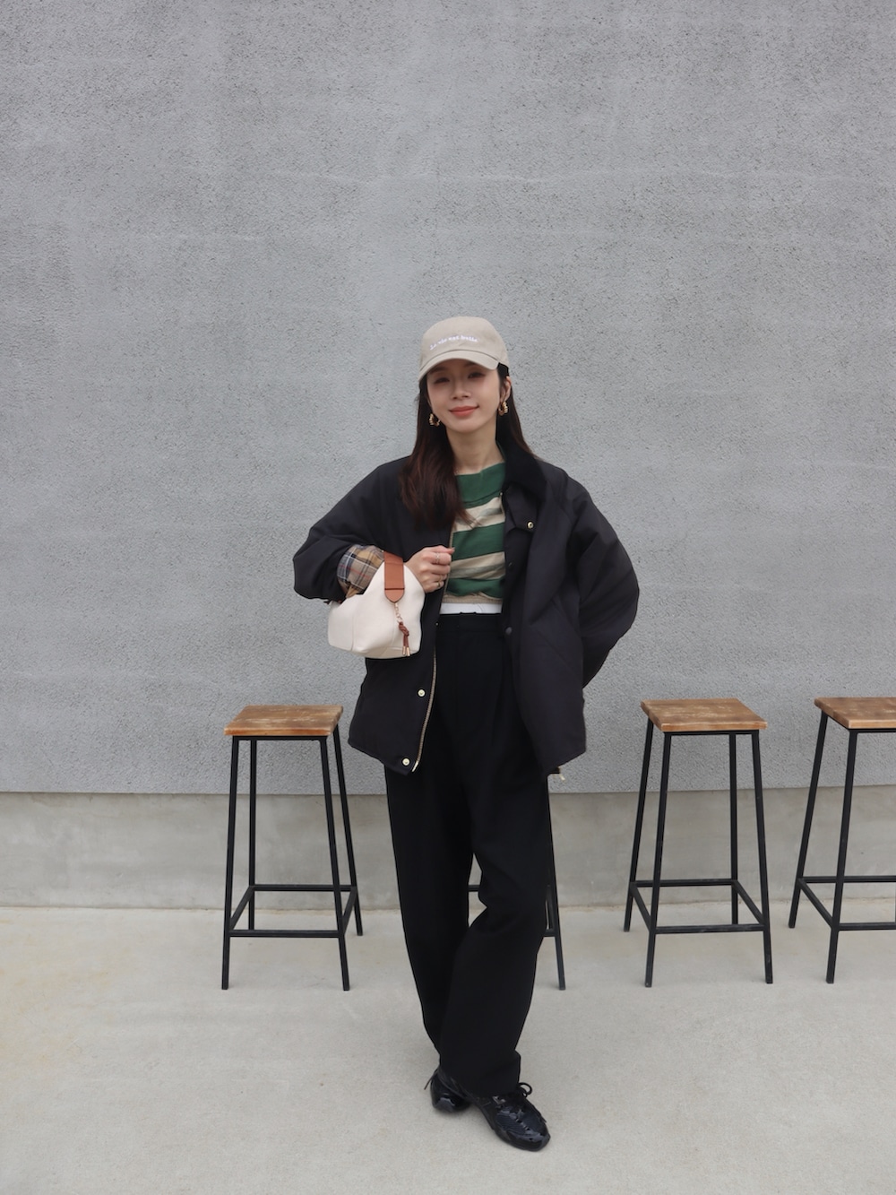 グリーン系のTシャツ/カットソー、ブラック系のその他アウター、ベージュ系のキャップを着用したレディースの春コーディネートの2枚目の写真