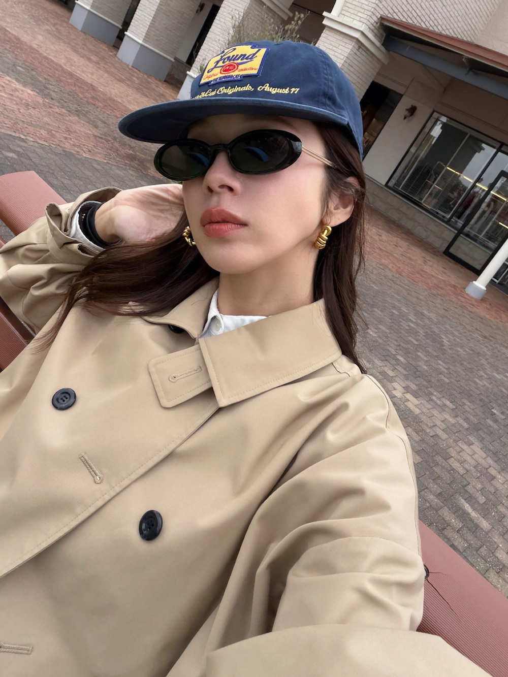 ベージュ系のトレンチコート、ブラック系のスニーカー、その他のキャップを着用したレディースの春コーディネートの2枚目の写真