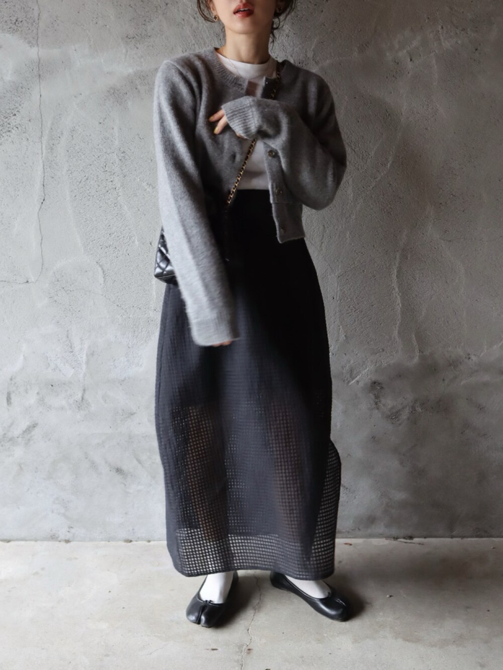 グレー系のカーディガン/ボレロ、ブラック系のスカート、ブラック系のバレエシューズを着用したレディースの冬コーディネートの2枚目の写真