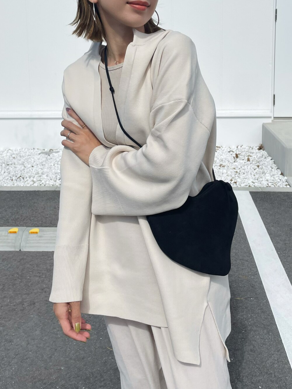 ホワイト系のニット/セーター、ホワイト系のスラックス、ホワイト系のスニーカーを着用したレディースの秋コーディネートの2枚目の写真