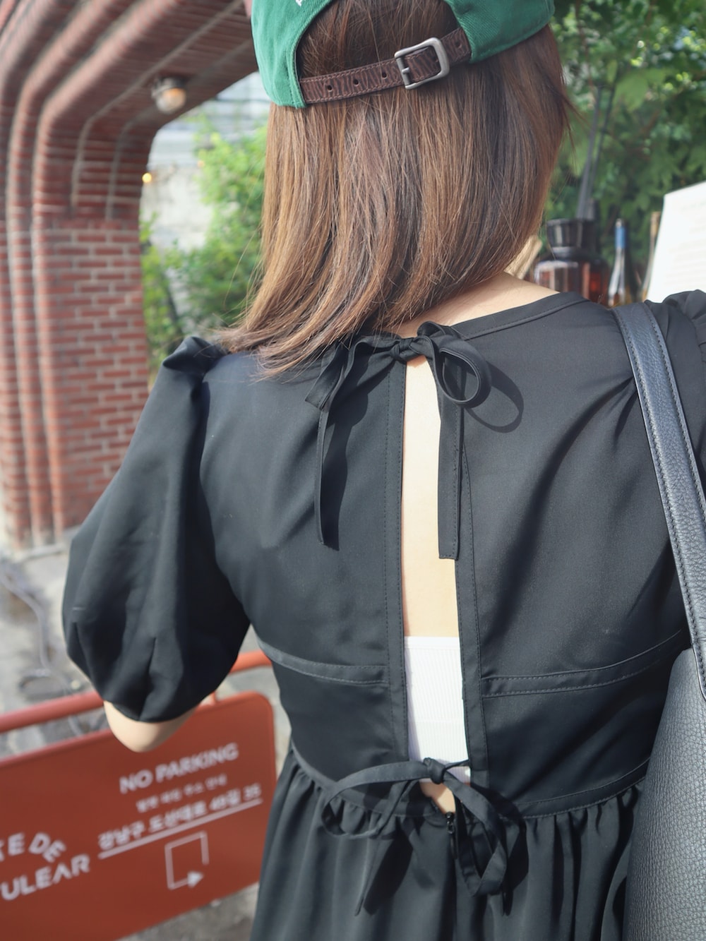 ブラック系のサンダル、ブラック系のワンピース、グリーン系のキャップを着用したレディースの夏コーディネートの3枚目の写真