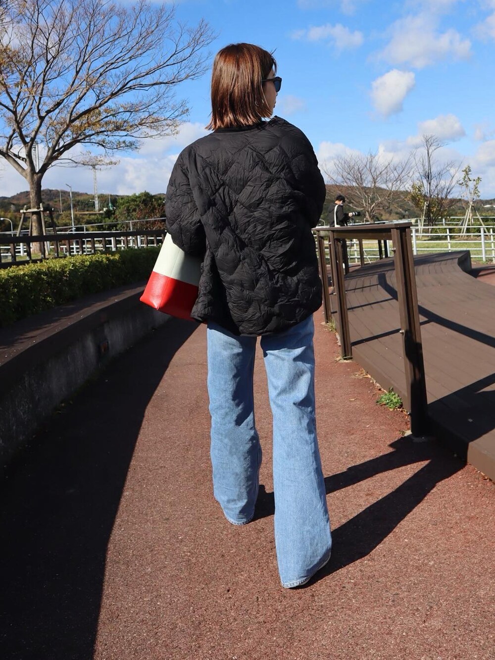 ブラック系のダウンジャケット/コート、ブラック系のニット/セーター、ブルー系のデニムパンツを着用したレディースの秋コーディネートの2枚目の写真