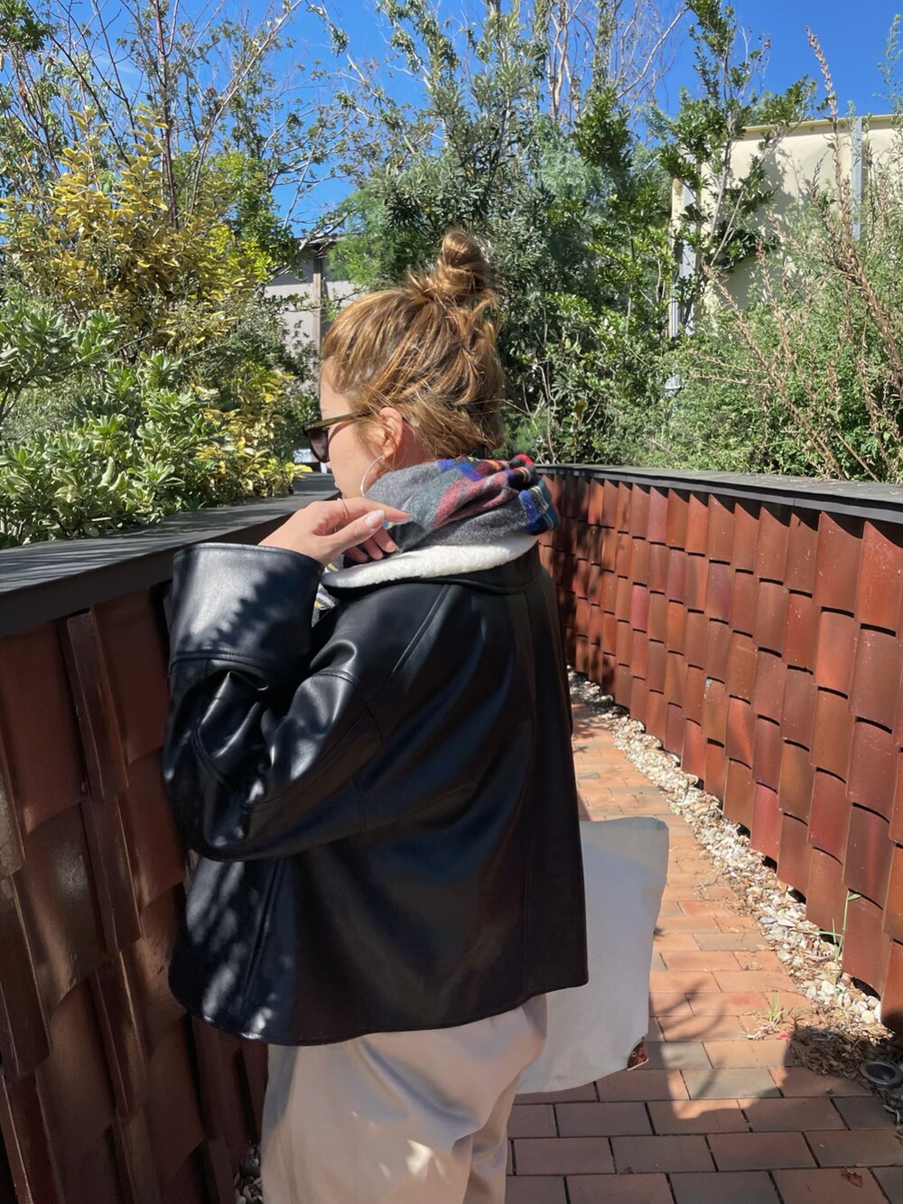 ブラック系のその他アウター、ベージュ系のチノパンツ、ブラック系のスニーカーを着用したレディースの秋コーディネートの3枚目の写真