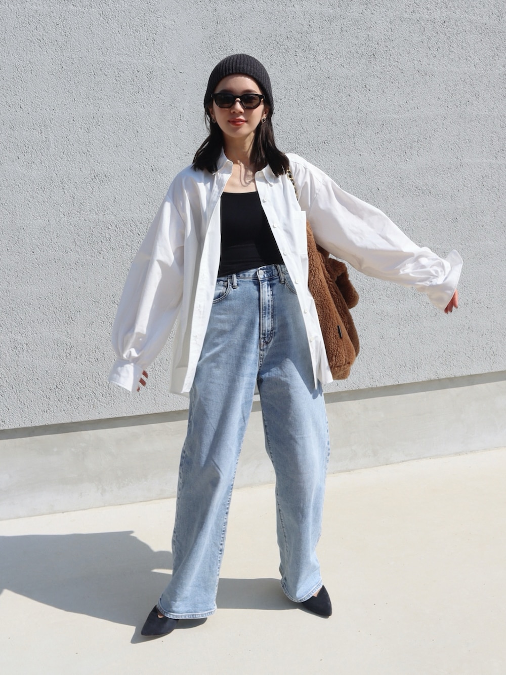 ブラウン系のトートバッグ、ホワイト系のシャツ/ブラウス、ブルー系のデニムパンツを着用したレディースの秋コーディネートの2枚目の写真