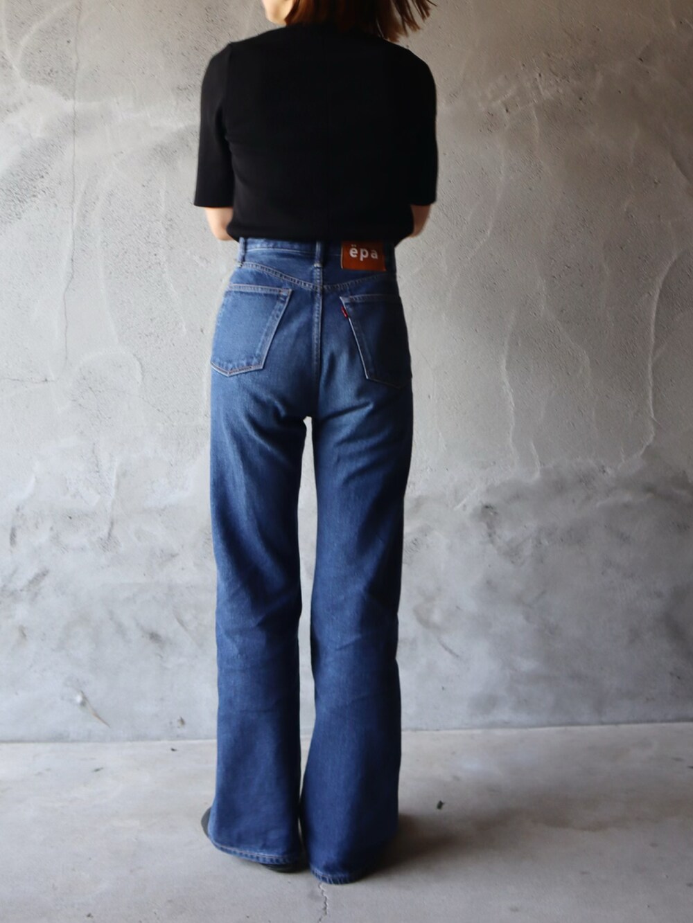 ブラック系のブルゾン、ブラック系のニット/セーター、ブルー系のデニムパンツを着用したレディースの春コーディネートの2枚目の写真