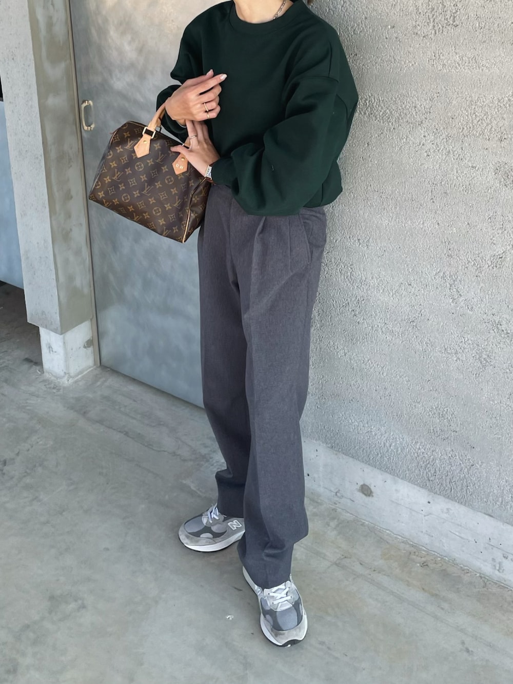 グリーン系のスウェット、グレー系のスラックス、ブラウン系のハンドバッグを着用したレディースの冬コーディネートの2枚目の写真