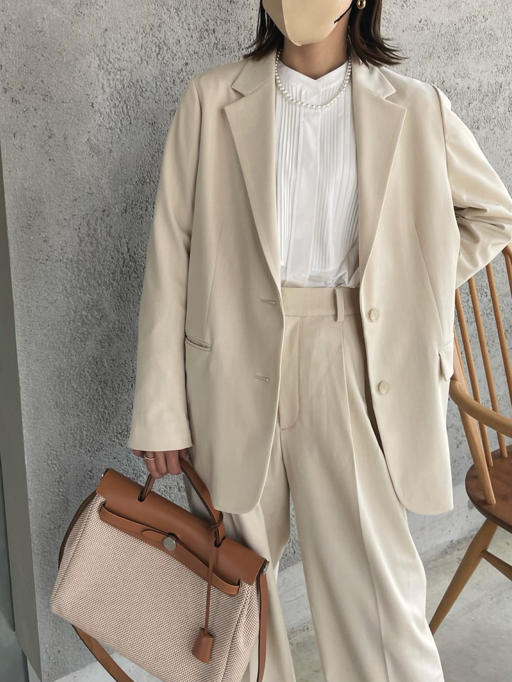 ベージュ系のテーラードジャケット、ホワイト系のスラックス、ベージュ系のハンドバッグを着用したレディースの冬コーディネートの2枚目の写真