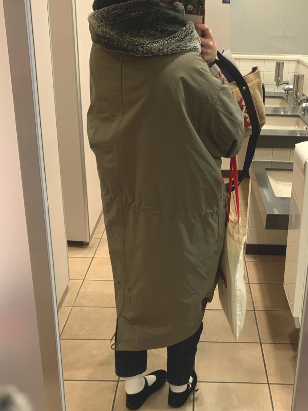 グリーン系のモッズコート、レッド系のショルダーバッグ、ブラック系のバレエシューズを着用したレディースの春コーディネートの2枚目の写真