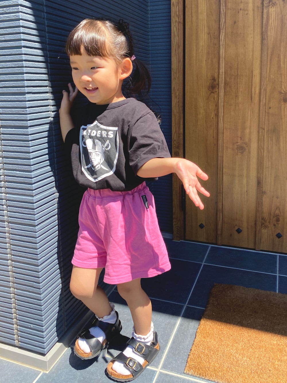 ピンク系のセットアップ、ブラック系のTシャツ/カットソー、ブラック系のサンダルを着用したキッズの夏コーディネートの2枚目の写真