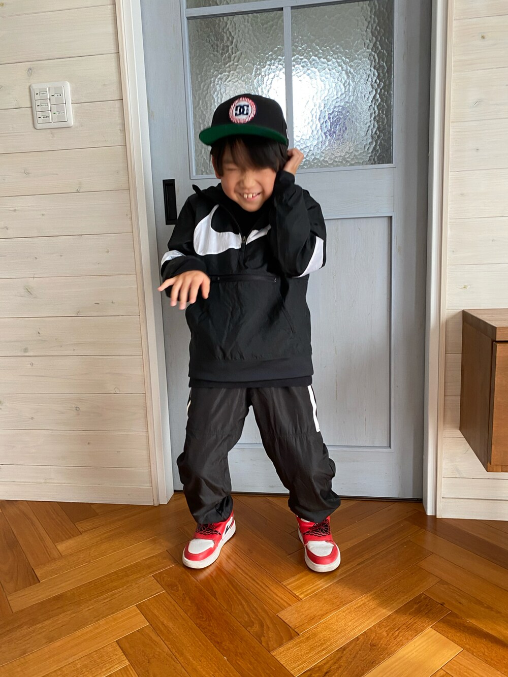ブラック系のマウンテンパーカー、ブラック系のその他パンツ、レッド系のスニーカーを着用したキッズの冬コーディネートの3枚目の写真