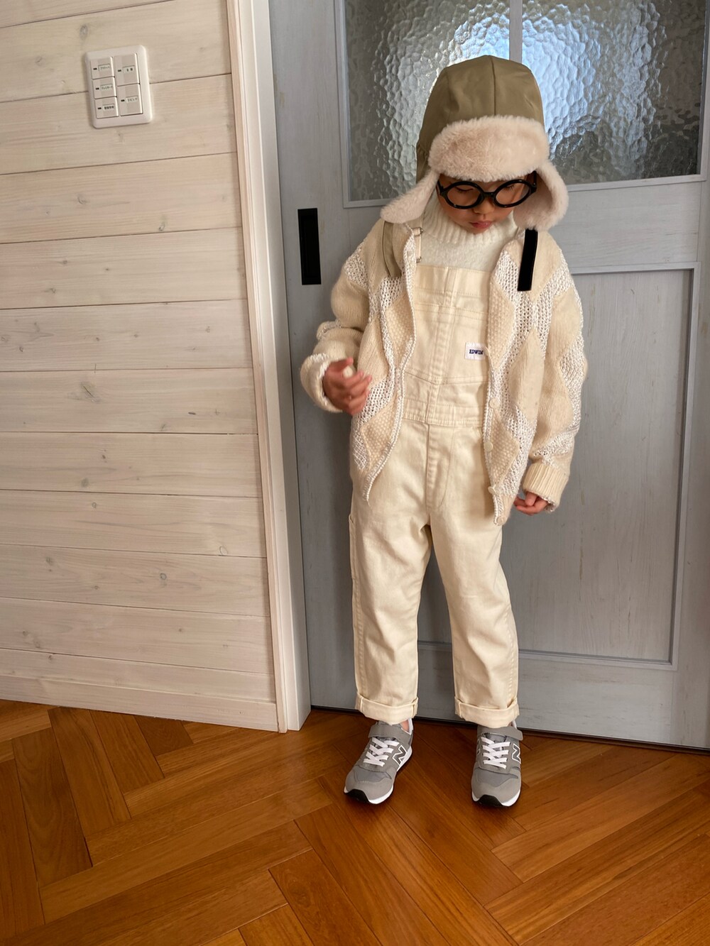 ホワイト系のサロペット/オーバーオール、グレー系のスニーカー、ホワイト系のニット/セーターを着用したキッズの冬コーディネートの2枚目の写真