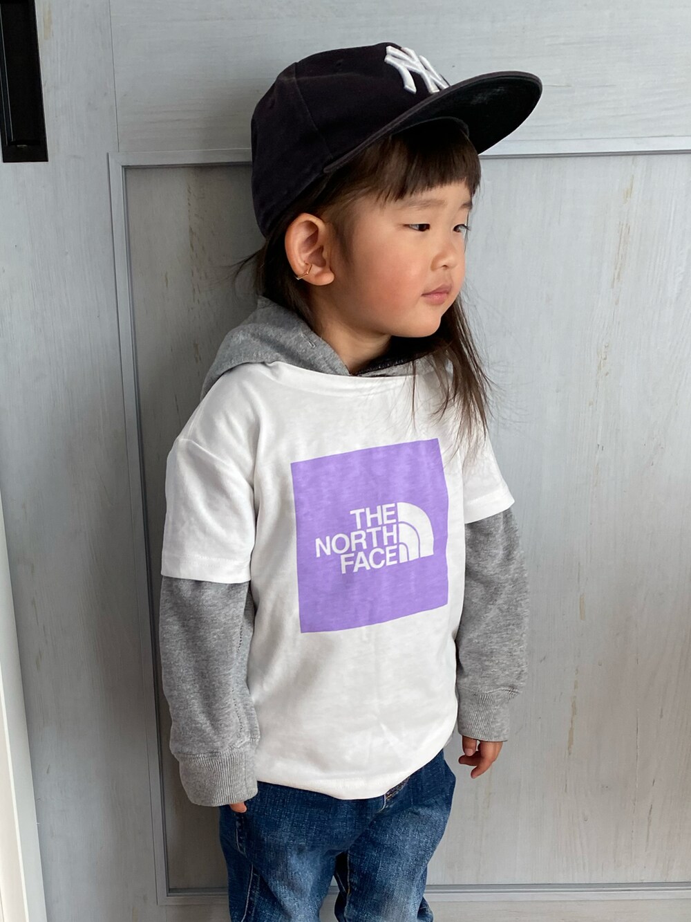 ホワイト系のTシャツ/カットソー、ホワイト系のスニーカー、ブルー系のキャップを着用したキッズの春コーディネートの2枚目の写真